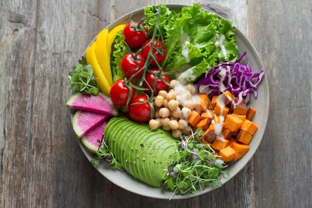 Healthy salad with tomatoes, lettuce, sweet potatoes, chickpeas, and avocados.